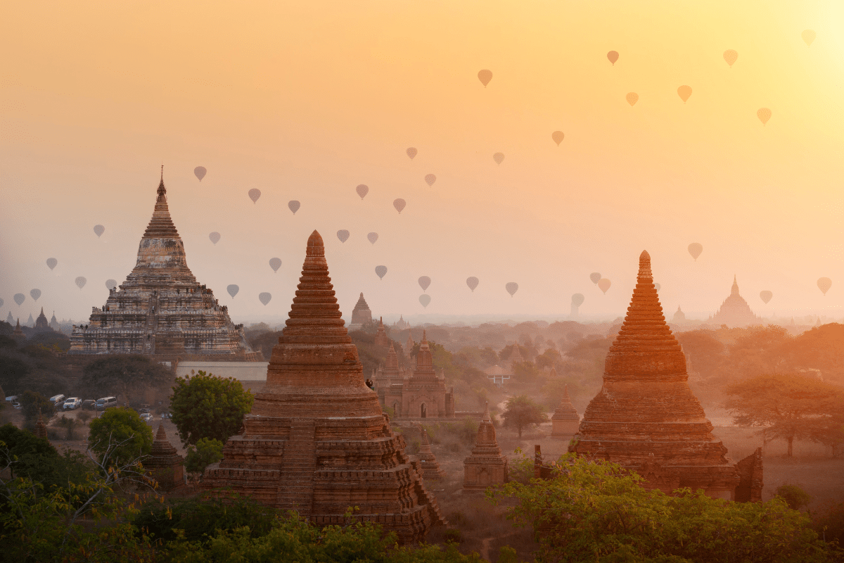Hot air balloons flying over ancient pagodas with beautiful sunrise