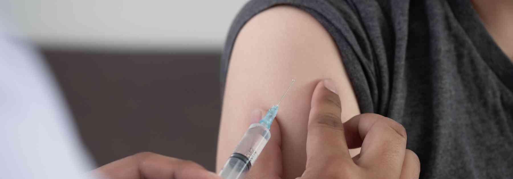 person wearing grey vest receiving vaccine in arm